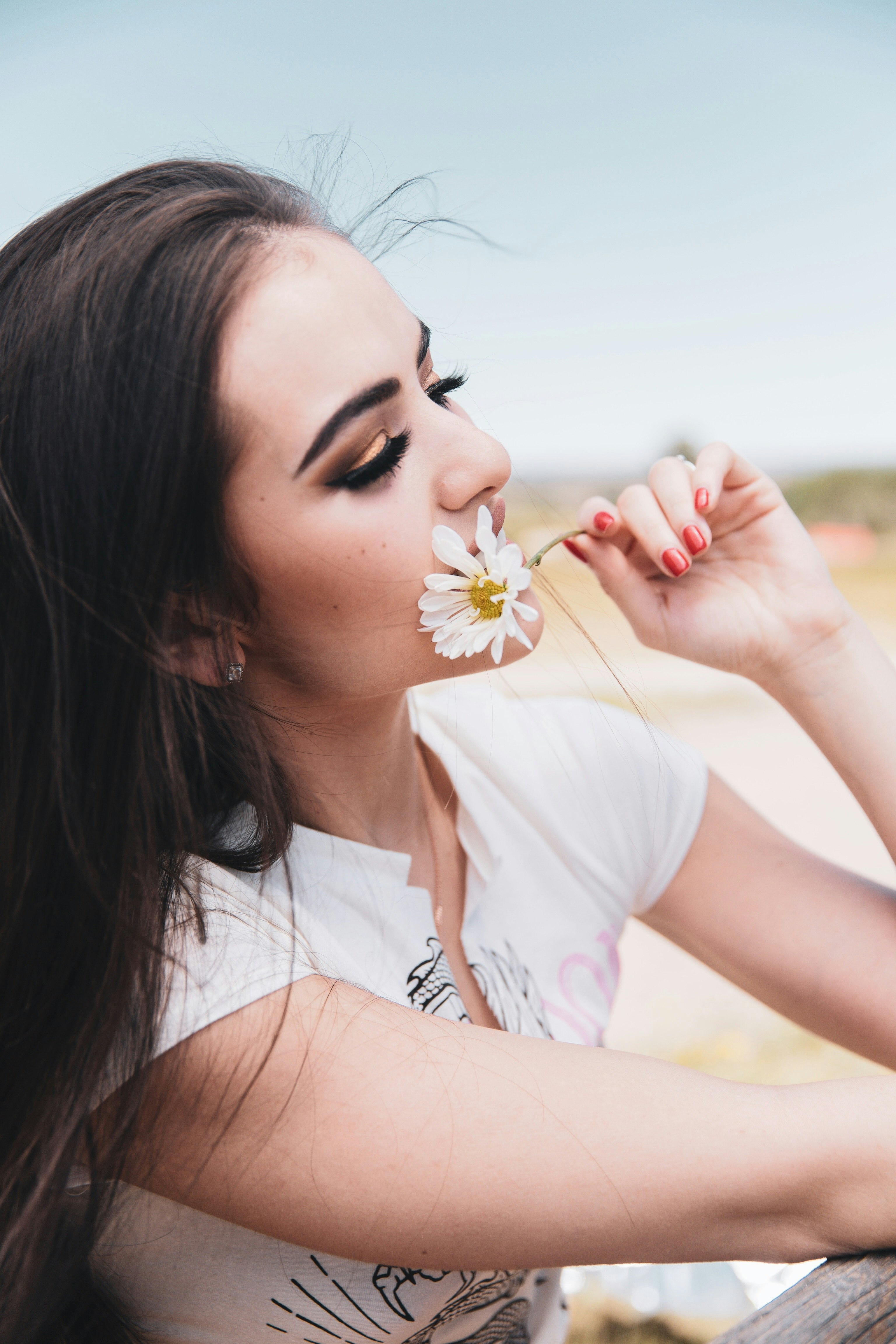 woman in white shirt holding white flower during daytime